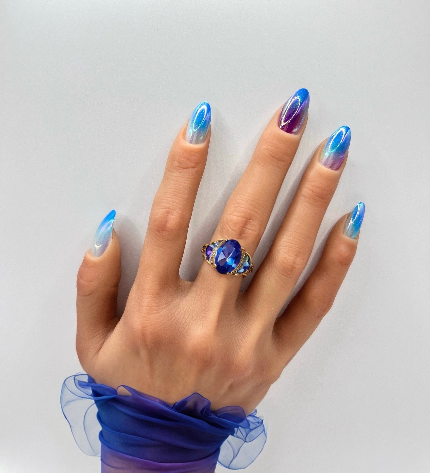 Hand with iridescent medium almond press-on nails in opal hues from Mani in Minutes, set name Aurora Glow.