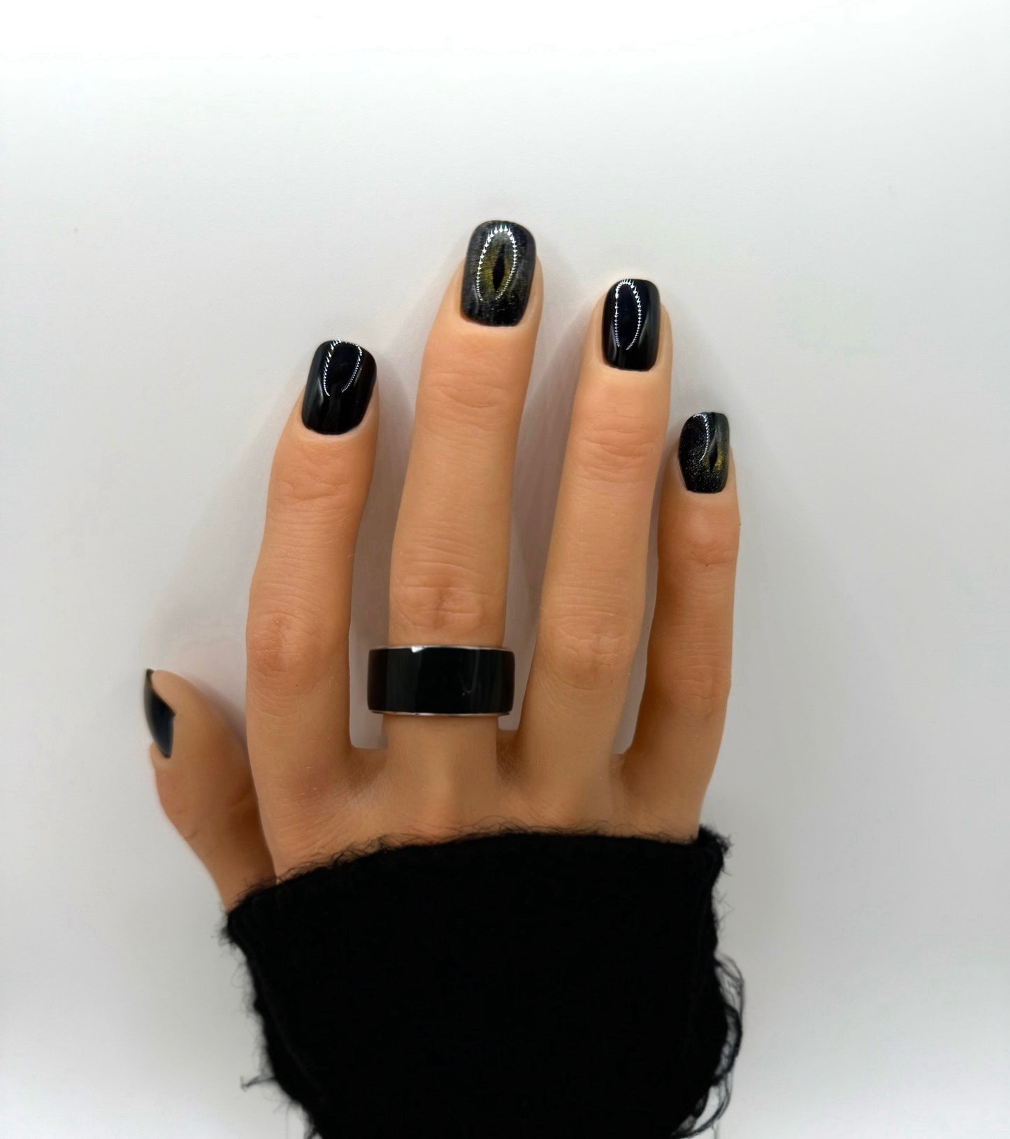 Hand wearing Cat Eye press-on nails – short square glossy black nails with shimmering feline accent detail