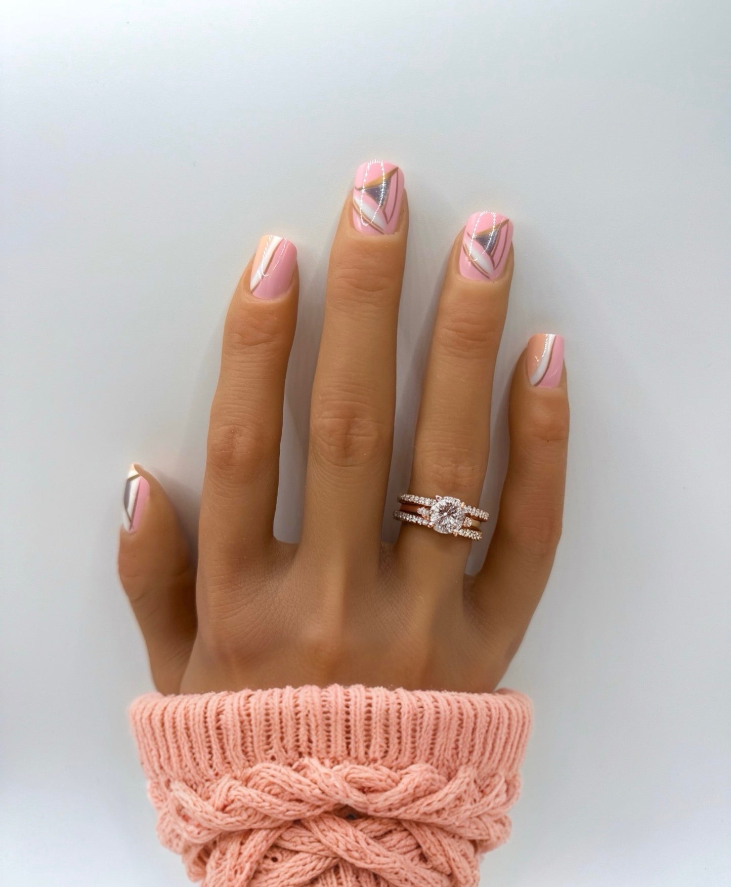 Hand wearing Vogue Lines press-on nails – medium square shape with pink base and geometric white, peach, and pewter accents