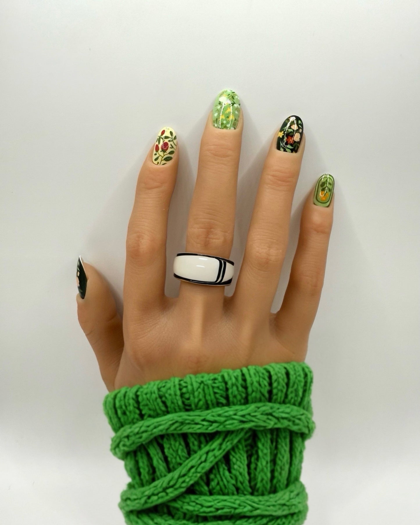 Model wearing Folk Garden press-on nails – medium oval shape with dark floral, botanical and folk-inspired nail art