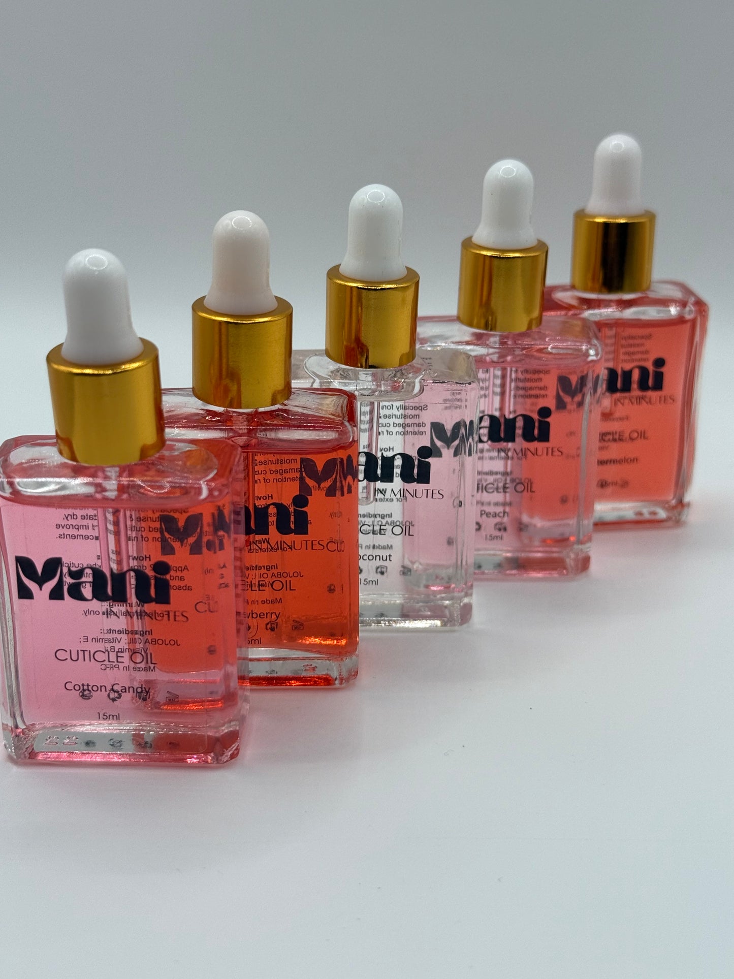 Mani in Minutes Cuticle Oil collection featuring multiple scent variations displayed side by side in labelled bottles.