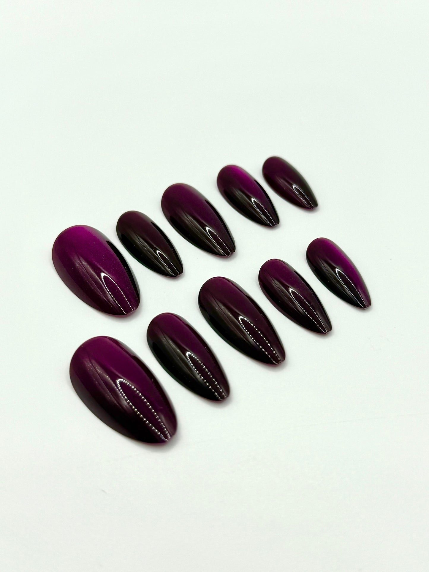 Close-up view of deep berry medium almond nails in the Noir Berry set.