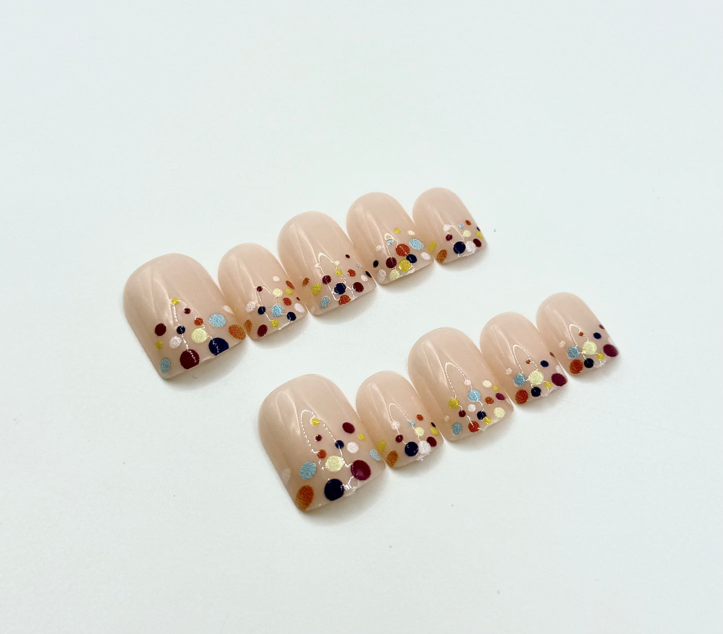 Close-up of Confetti Pop press-on nails showing colourful confetti dot design on nude background
