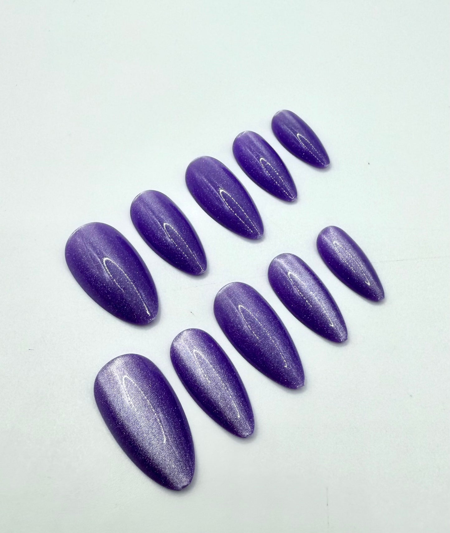 Close-up of Purple Luxe press-on nails showing medium almond shape and vibrant metallic purple shimmer