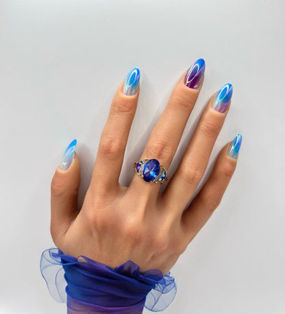 Hand with iridescent medium almond press-on nails in opal hues from Mani in Minutes, set name Aurora Glow.