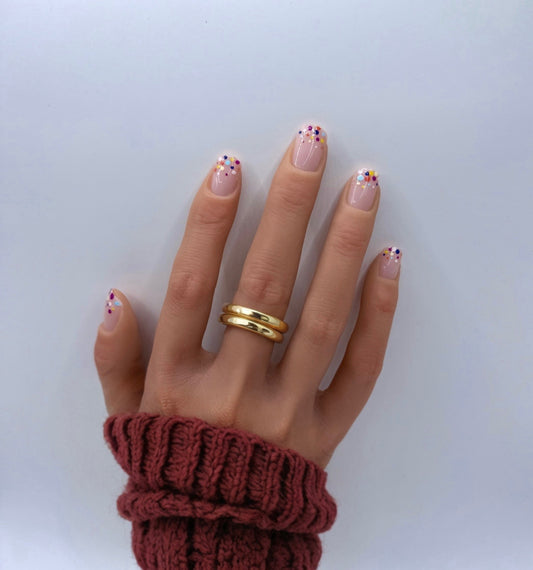 Hand wearing Confetti Pop press-on nails – short square nude nails with multicolour dot accents