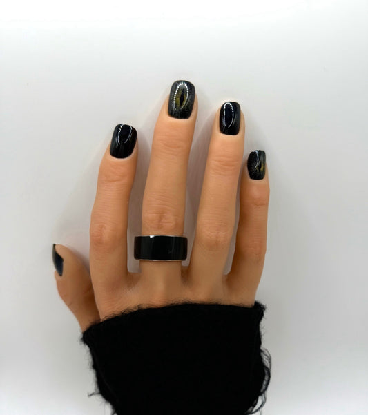 Hand wearing Cat Eye press-on nails – short square glossy black nails with shimmering feline accent detail