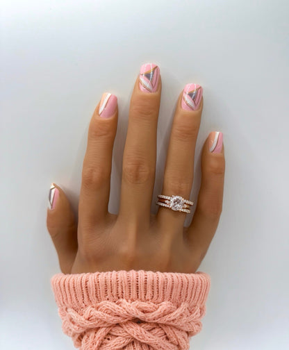 Hand wearing Vogue Lines press-on nails – medium square shape with pink base and geometric white, peach, and pewter accents