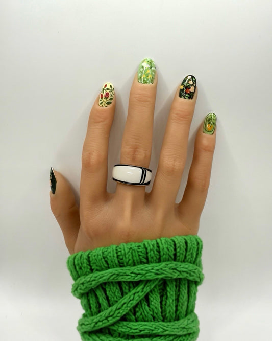 Model wearing Folk Garden press-on nails – medium oval shape with dark floral, botanical and folk-inspired nail art