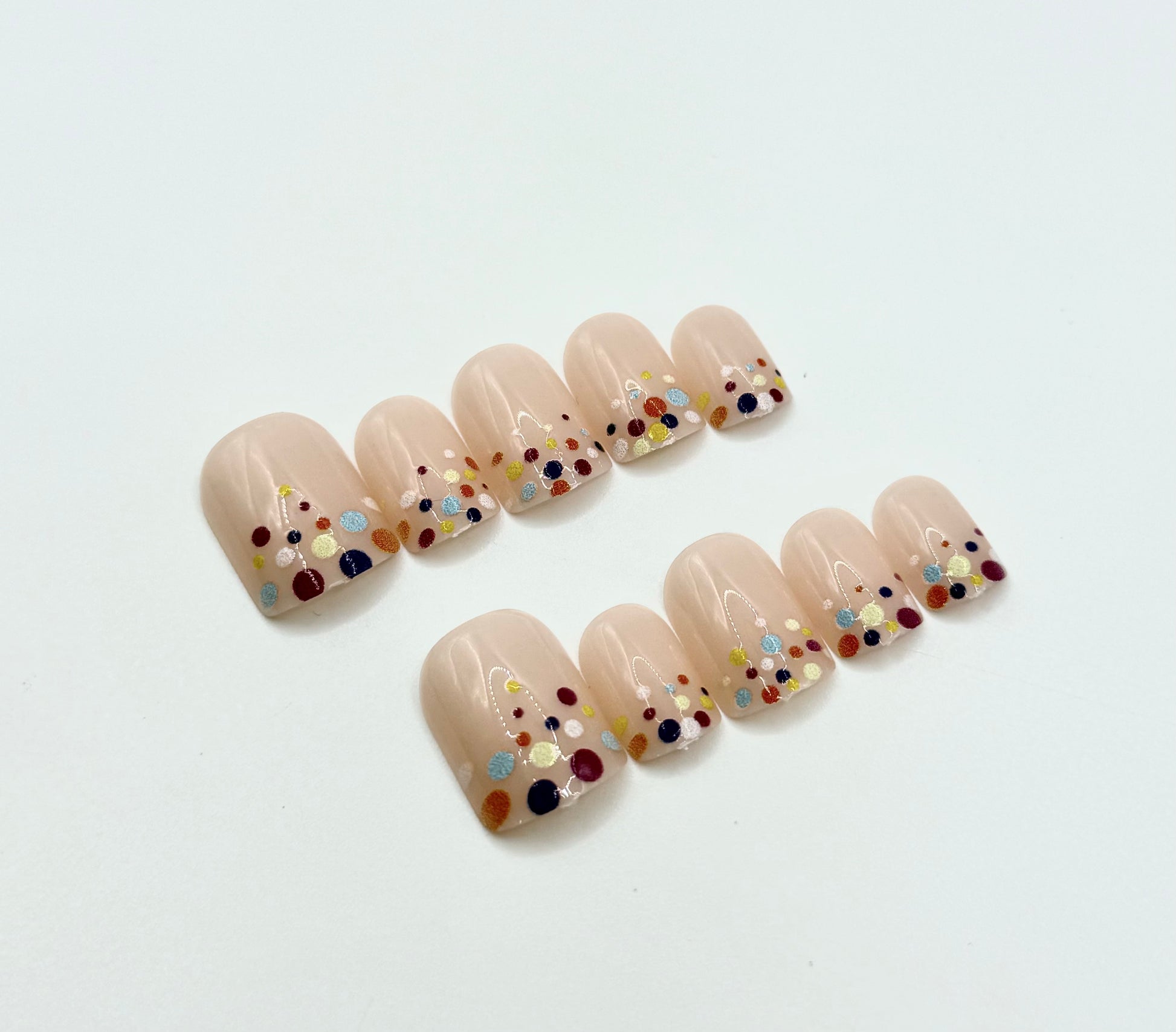 Close-up of Confetti Pop press-on nails showing colourful confetti dot design on nude background