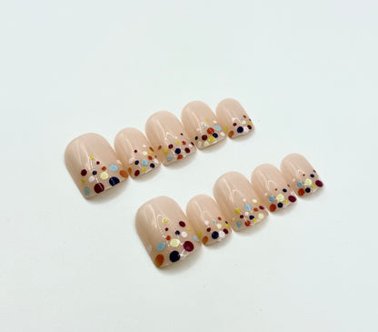 Close-up of Confetti Pop press-on nails showing colourful confetti dot design on nude background
