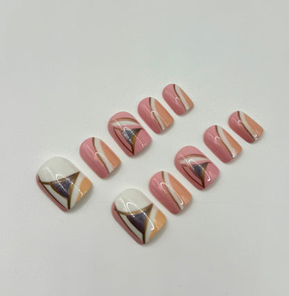 Close-up of Vogue Lines press-on nails showing modern geometric patterns in pink, white, peach, and silvery pewter