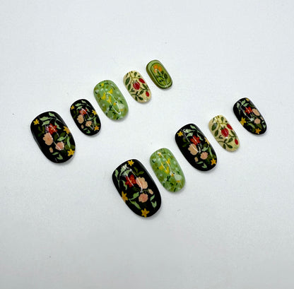 Close-up of Folk Garden press-on nails showing a mix of earthy green, black, and cream tones with detailed folk floral designs