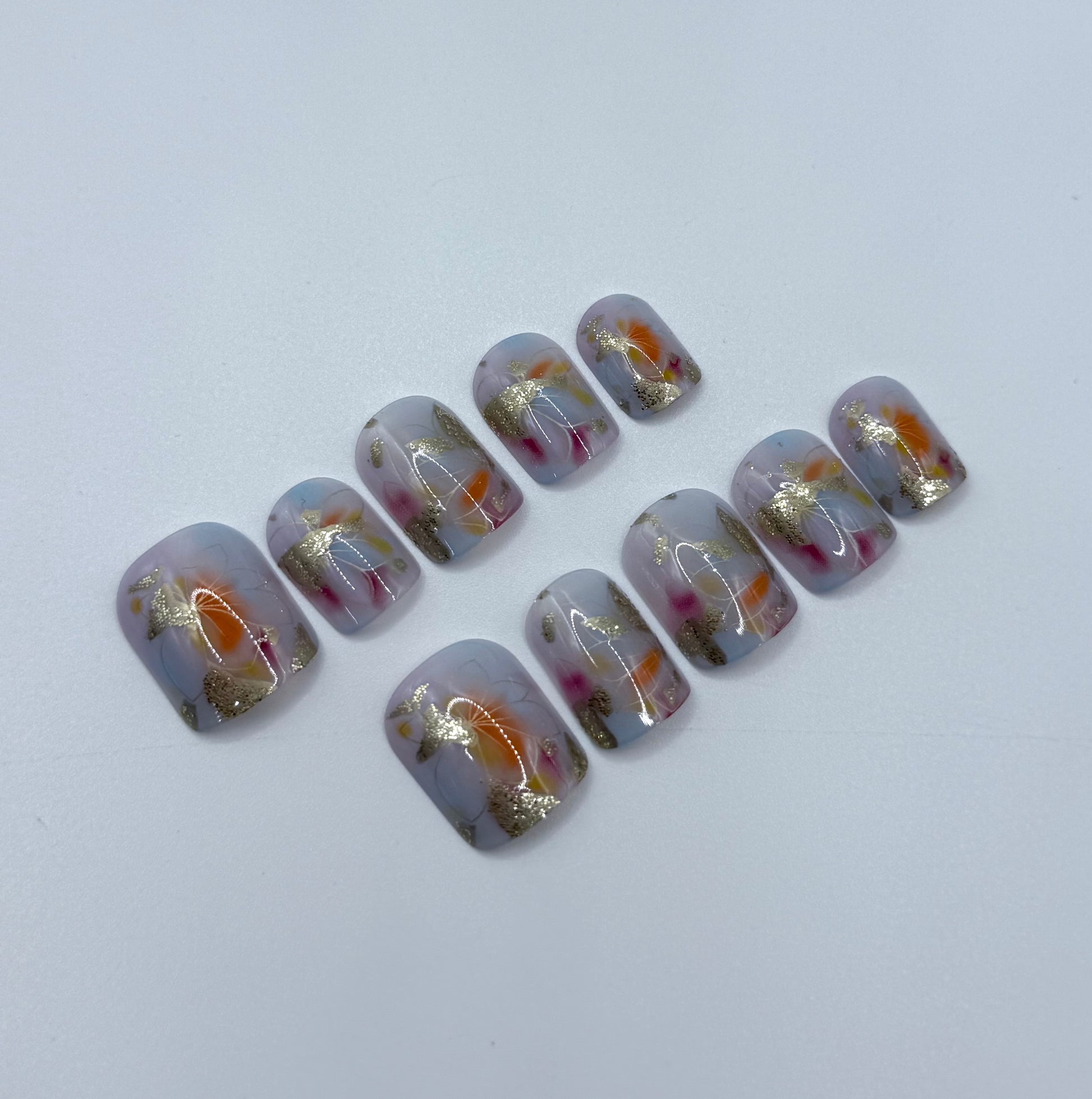 Artistic watercolour manicure with pink, blue, and gold details